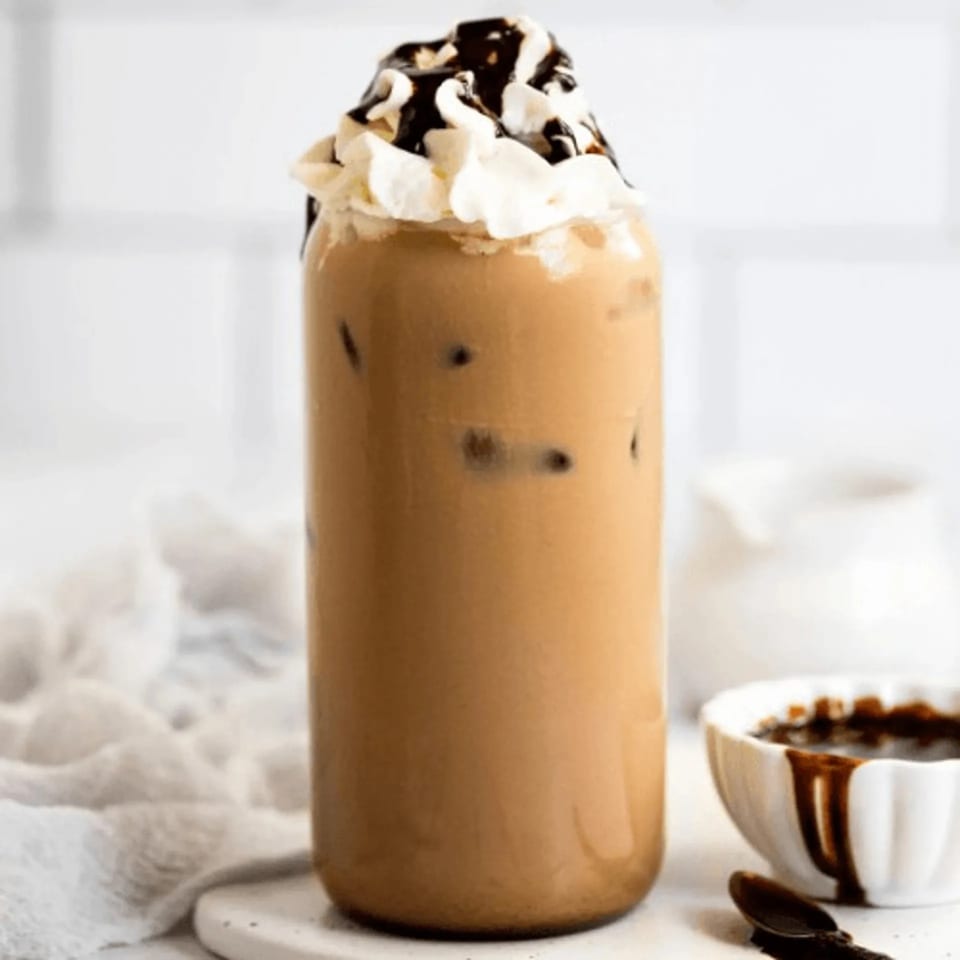 Iced coffee with whipped cream and chocolate drizzle in a tall glass at Java House.